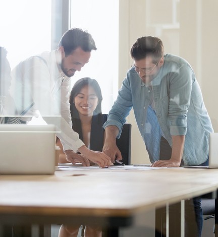 two men and a women looking over documents in an office setting